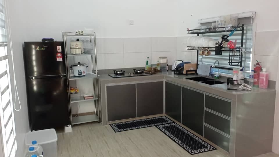 Dapur lengkap dengan peralatan memasak moden dan kabinet besar di homestay Pokok Sena